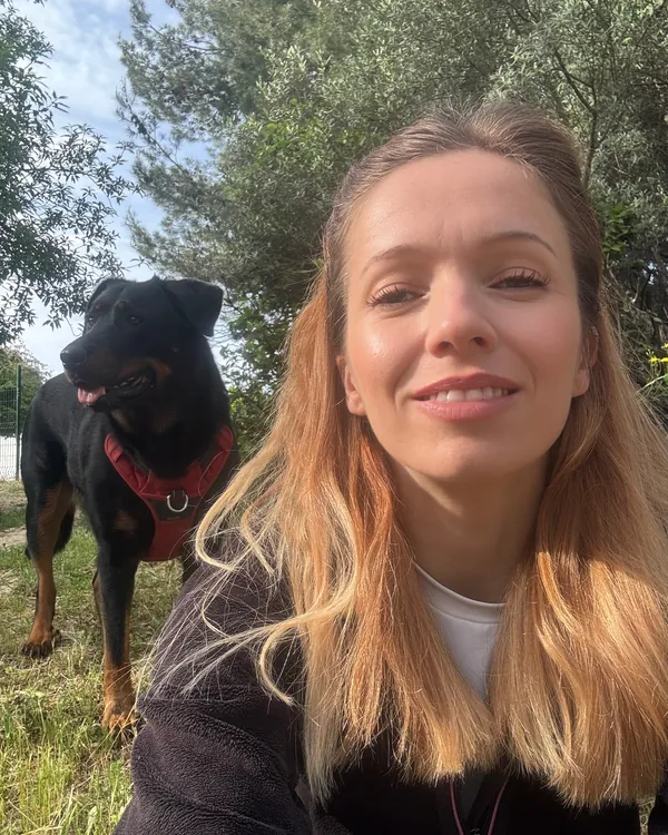 Selfie de Marie-Ange avec son beauceron au harnais rouge