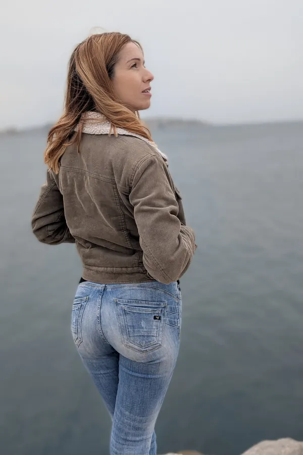 Marie-Ange de dos sur les rochers, face à la mer par temps gris