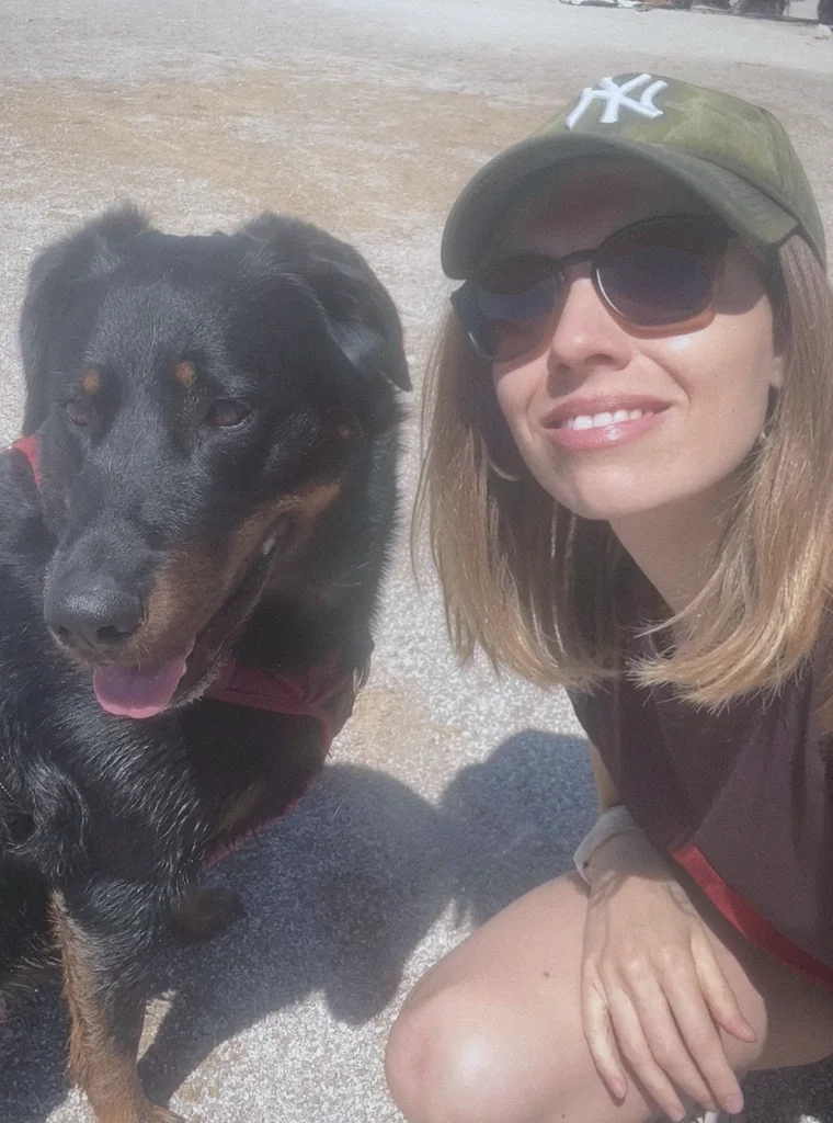 Selfie de Marie-Ange en casquette et lunettes de soleil, joue contre son beauceron