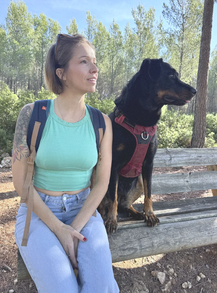 Marie-Ange assise sur un banc en pinède, son beauceron à côté d’elle